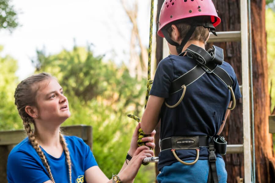 A child being helped with a harness during an activity.